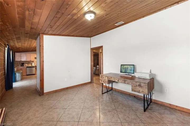 Office with wooden ceiling, light tile patterned flooring, visible vents, and baseboards
