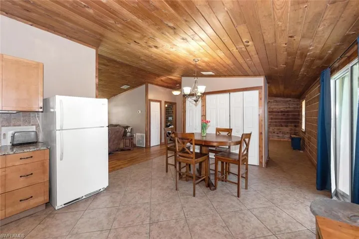 Dining room featuring wooden ceiling, light tile patterned floors, a chandelier, and vaulted ceiling