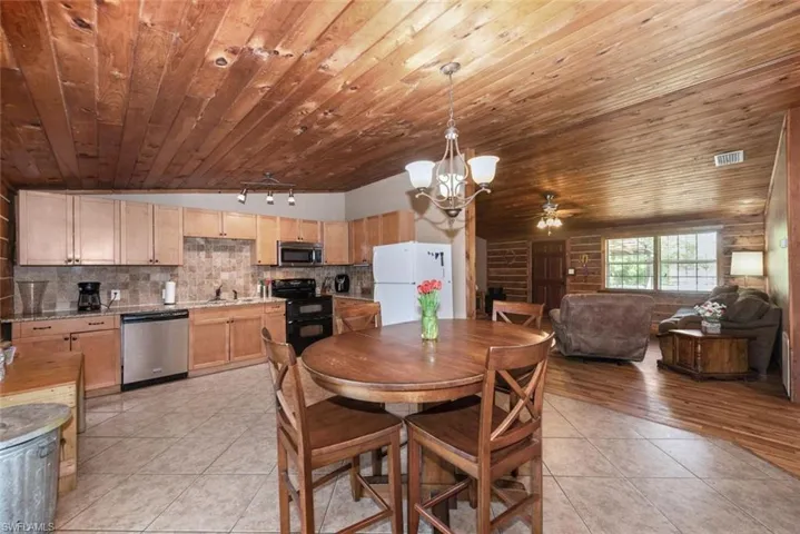 Dining area with ceiling fan with notable chandelier, light tile patterned floors, wood ceiling, and visible vents