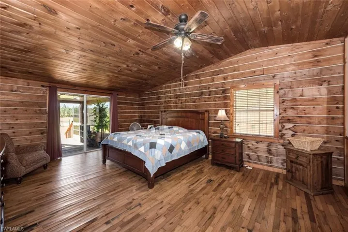 Bedroom featuring wood ceiling, hardwood / wood-style floors, vaulted ceiling, and access to outside