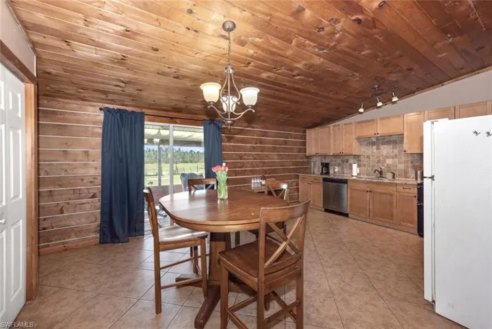 Dining space featuring light tile patterned floors, a notable chandelier, wooden ceiling, and lofted ceiling