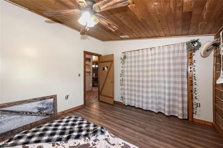 Bedroom with dark wood finished floors, wood ceiling, baseboards, and ceiling fan