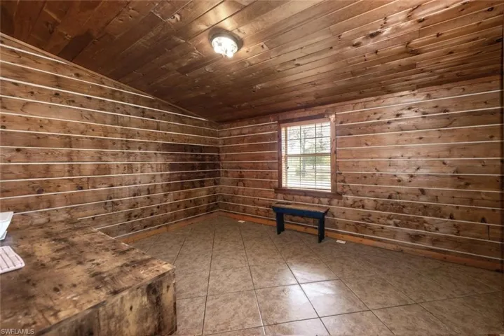 Empty room featuring lofted ceiling, dark tile patterned flooring, and wood ceiling