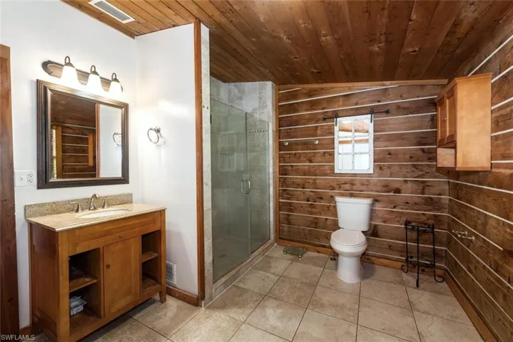 Bathroom with tile patterned floors, toilet, wood ceiling, and visible vents