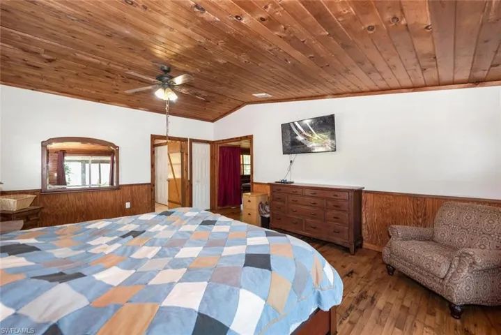 Bedroom featuring a wainscoted wall, wooden ceiling, lofted ceiling, and wood-type flooring