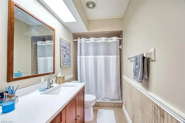 Full bathroom with visible vents, a shower stall, a wainscoted wall, toilet, and tile patterned floors