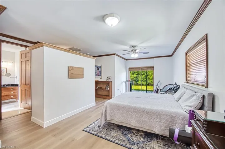 Bedroom with visible vents, light wood-type flooring, crown molding, and baseboards