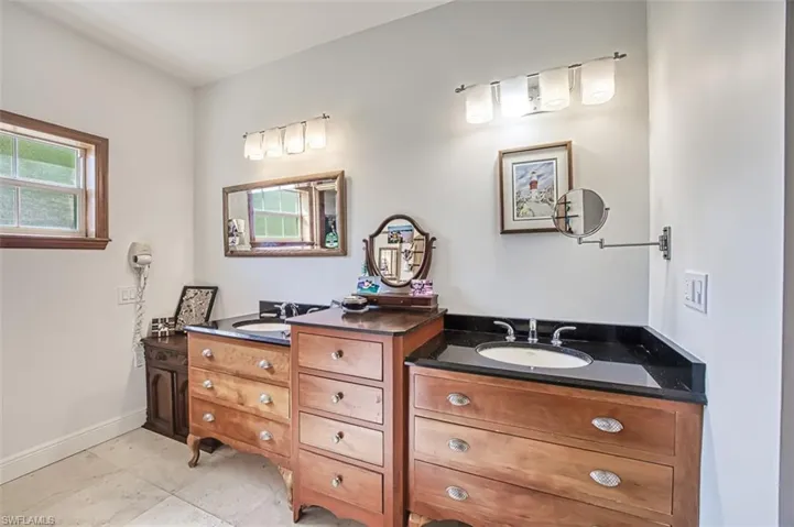 Full bath featuring two vanities, baseboards, and a sink