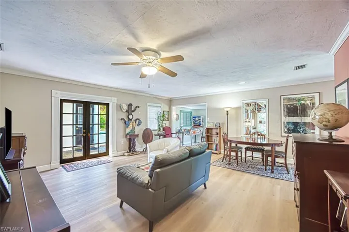 Living room featuring baseboards, visible vents, light wood-style floors, french doors, and a textured ceiling
