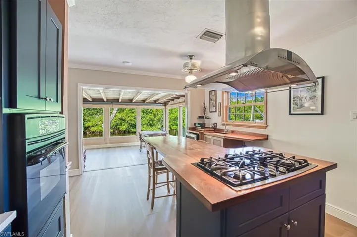 Kitchen with visible vents, black appliances, island exhaust hood, a sink, and a textured ceiling