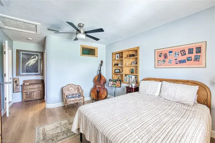 Bedroom featuring attic access, wood finished floors, baseboards, and ceiling fan