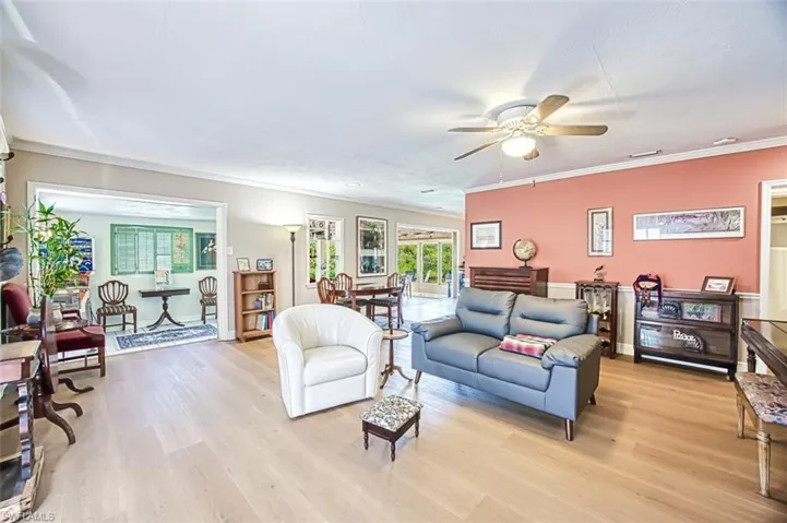 Living area with light wood-type flooring, a ceiling fan, and crown molding