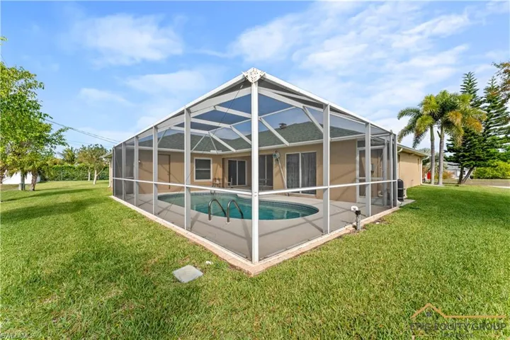 Rear view of property with a sunroom, a yard, an outdoor pool, a lanai, and a patio