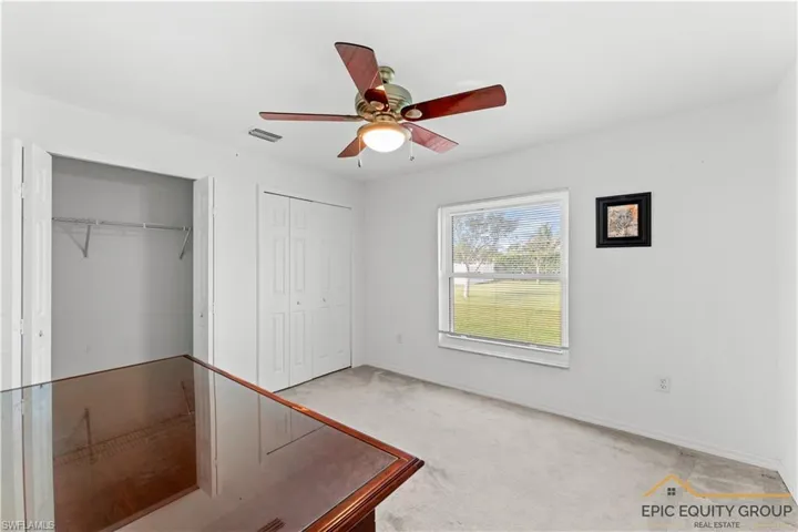 Unfurnished bedroom featuring light colored carpet, a ceiling fan, and two closets