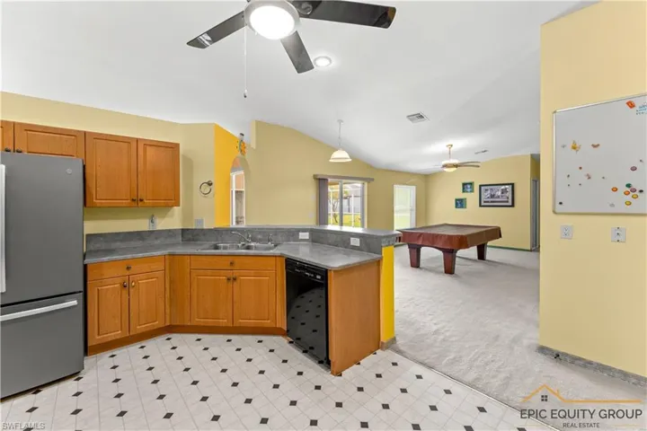 Kitchen featuring freestanding refrigerator, open floor plan, light carpet, decorative light fixtures, and billiards table