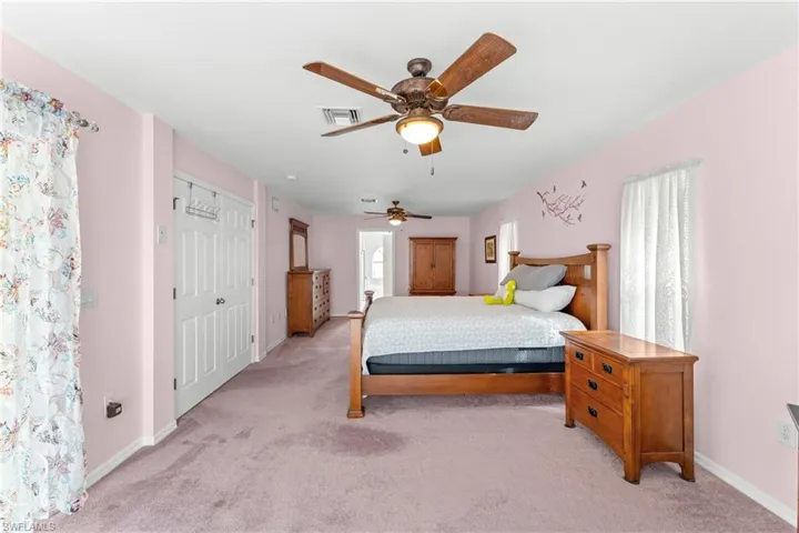 Bedroom with ceiling fan, light carpet, a closet, and ensuite bath