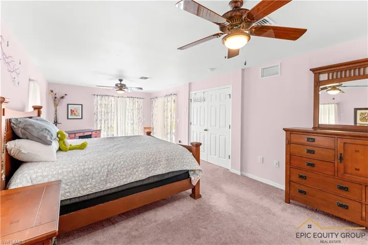 Bedroom with a closet, ceiling fan, and light colored carpet