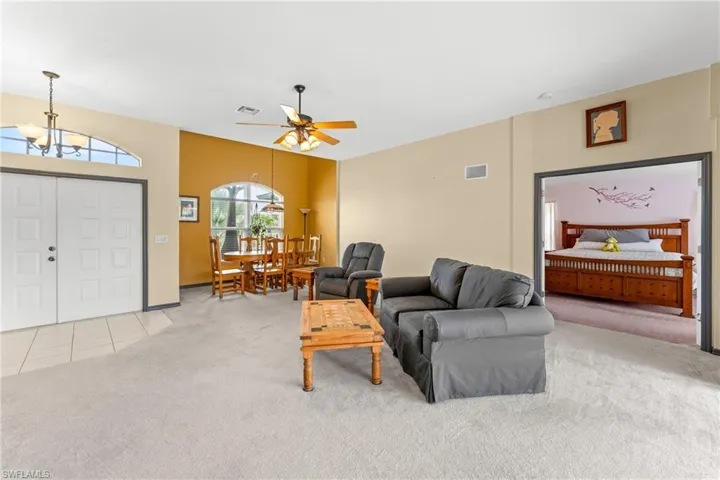 Living area featuring light colored carpet, ceiling fan, a chandelier, and light tile patterned flooring