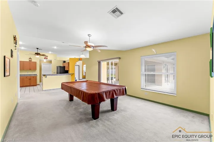 Recreation room with billiards, light colored carpet, a ceiling fan, arched walkways, and lofted ceiling