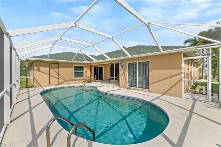 Swimming pool with a sunroom, a patio area, and glass enclosure