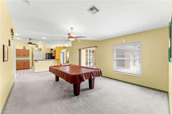 Recreation room featuring billiards table, light carpet, ceiling fan, and arched walkways