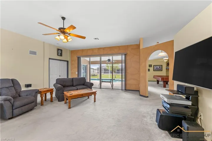 Living area featuring ceiling fan, light carpet, arched walkways, and billiards table