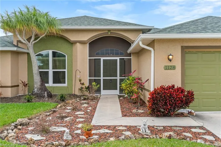 Property entrance with stucco siding, a shingled roof, a garage, and a sunroom