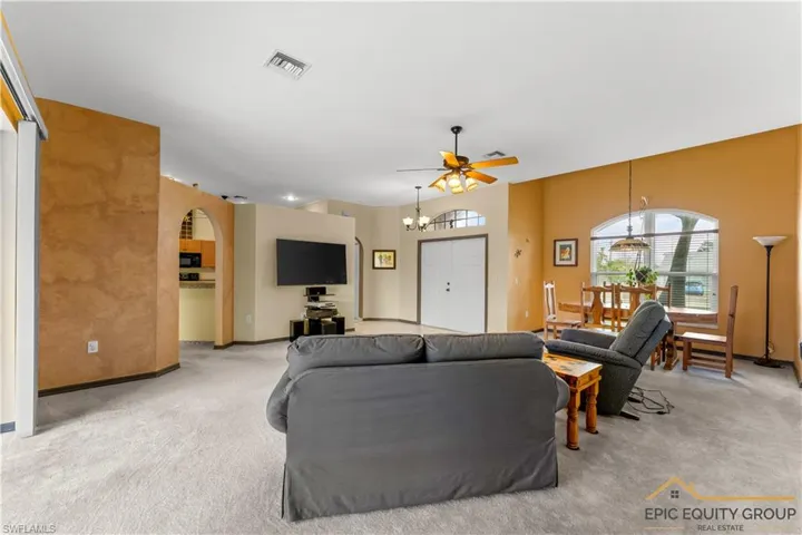 Living area featuring light colored carpet, arched walkways, a ceiling fan, and hanging lights
