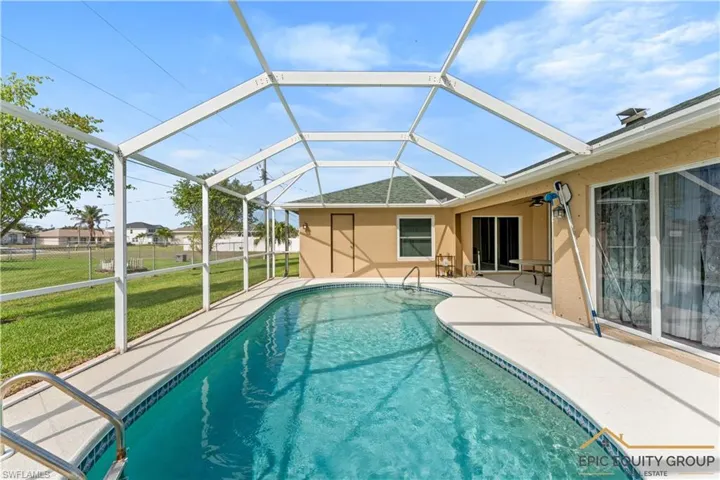 Outdoor pool featuring a sunroom, glass enclosure, and a patio