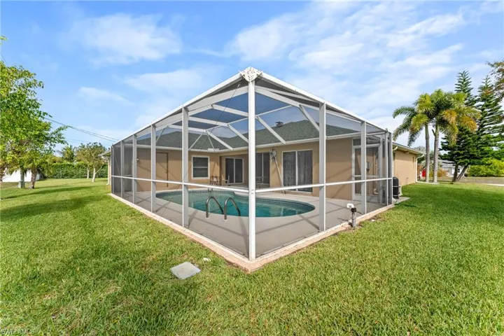 Rear view of property with a sunroom, a lawn, an outdoor pool, a lanai, and a patio area