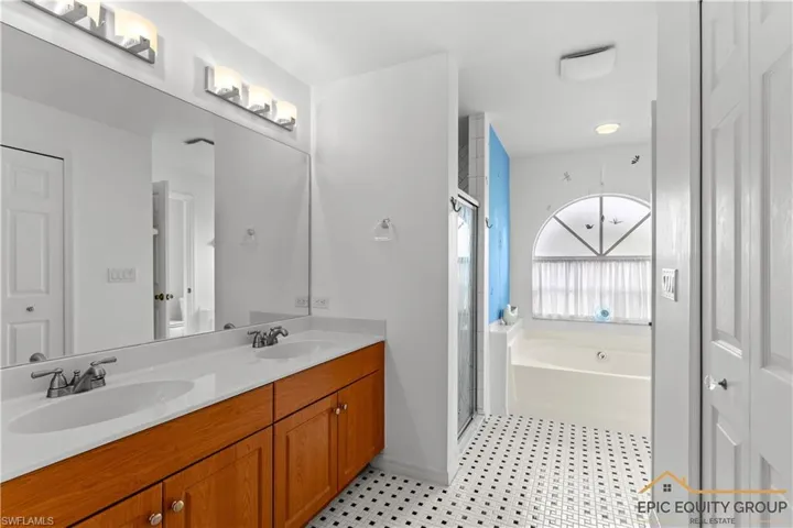 Full bathroom with double vanity, a bath, and a shower stall