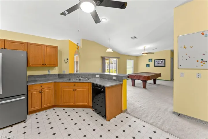 Kitchen with freestanding refrigerator, light colored carpet, open floor plan, lofted ceiling, and billiards