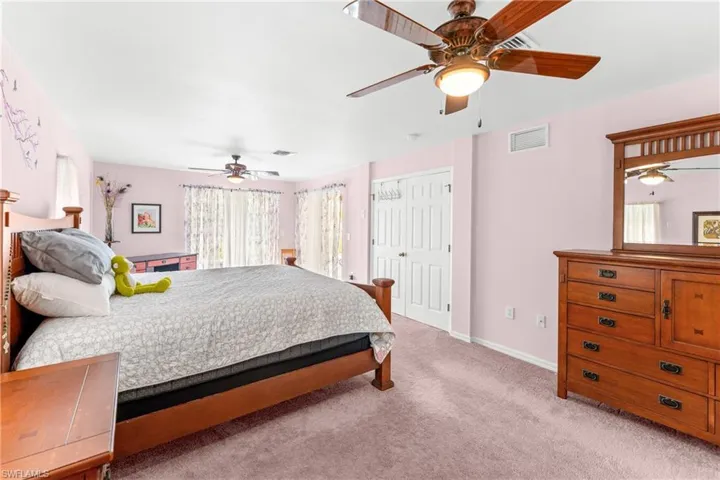 Bedroom with a closet, a ceiling fan, and light carpet