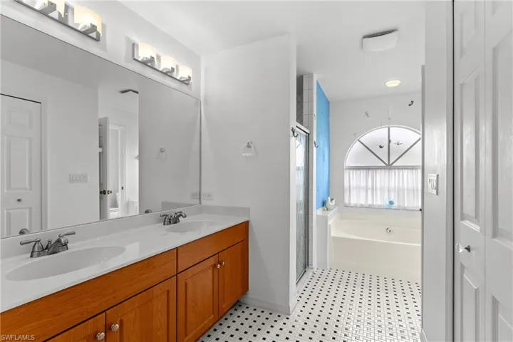 Full bathroom featuring double vanity, a garden tub, and a stall shower