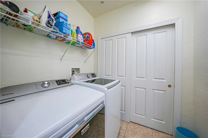 Laundry area with washing machine and dryer and light tile patterned floors