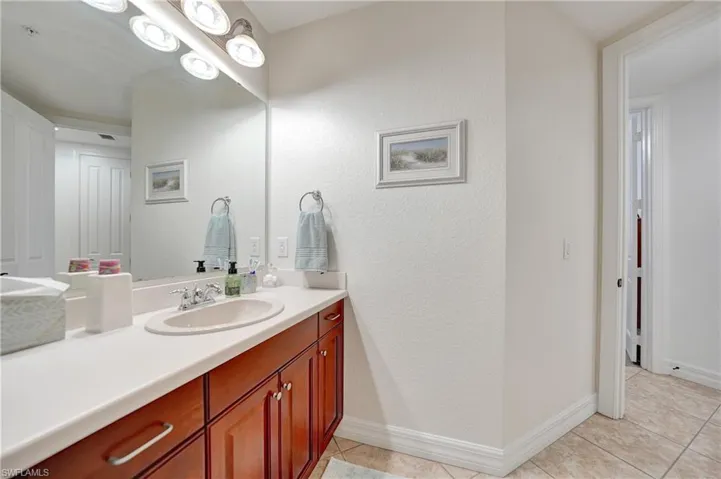 Bathroom with light tile patterned floors, vanity, and a textured wall