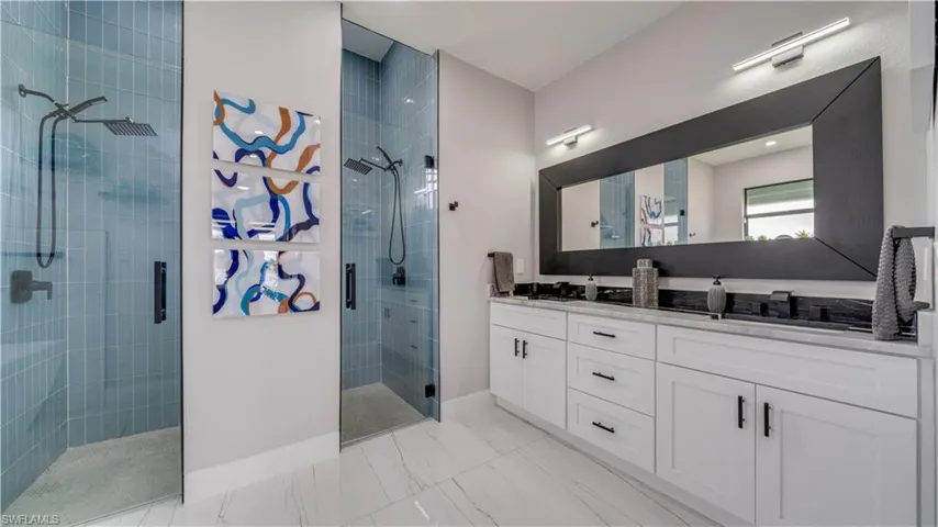 Primary bath double vanity with granite counter and custom wood cabinets