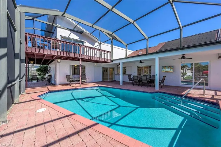 Swimming pool featuring ceiling fan, a patio, outdoor dining area, and glass enclosure