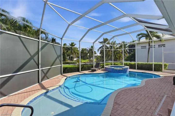 View of pool featuring a patio, a pool with connected hot tub, a sunroom, and glass enclosure