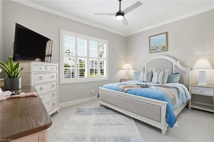Bedroom with crown molding, light tile patterned floors, and ceiling fan