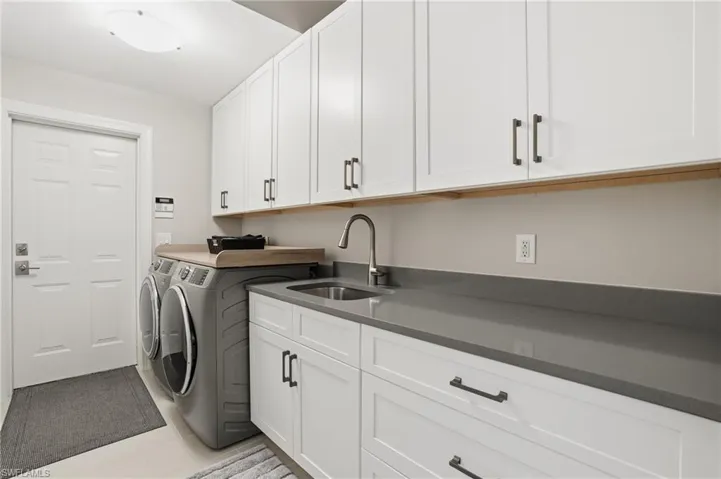 Washroom featuring separate washer and dryer, light tile patterned floors, and cabinet space
