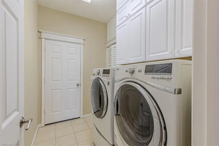 Laundry room with tile flooring, independent washer and dryer & built in cabinets.