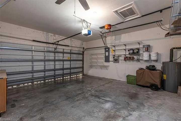 Garage featuring water heater, a garage door opener & electric panel.