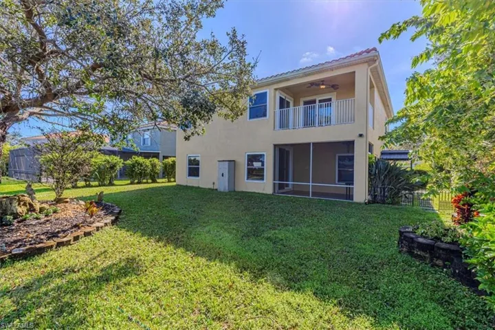 Rear view of Property with a Lawn, Stucco Siding, Balcony, & Screened Patio.