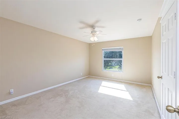 Room with light carpet & ceiling fan.