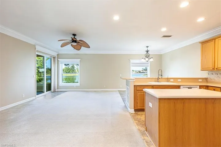 Kitchen with light countertops, island, plenty of natural light, crown molding & recessed lighting.