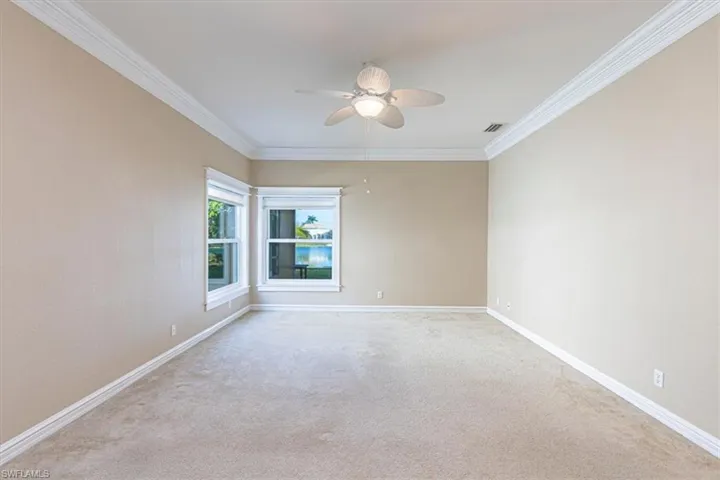 Room with crown molding, carpet flooring & ceiling fan.