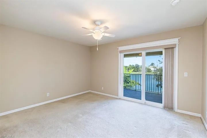 Room with water view, light carpet, & ceiling fan.