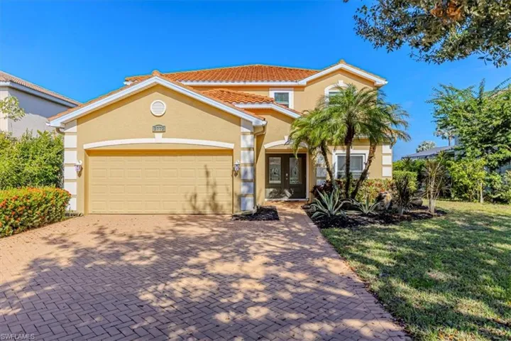 Front of home w/ stucco siding, decorative driveway, attached 2 car garage, tile roof & French doors.
