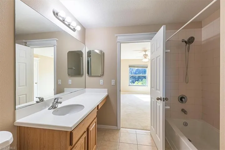 Bathroom with vanity, shower / bathtub combination, light tile.